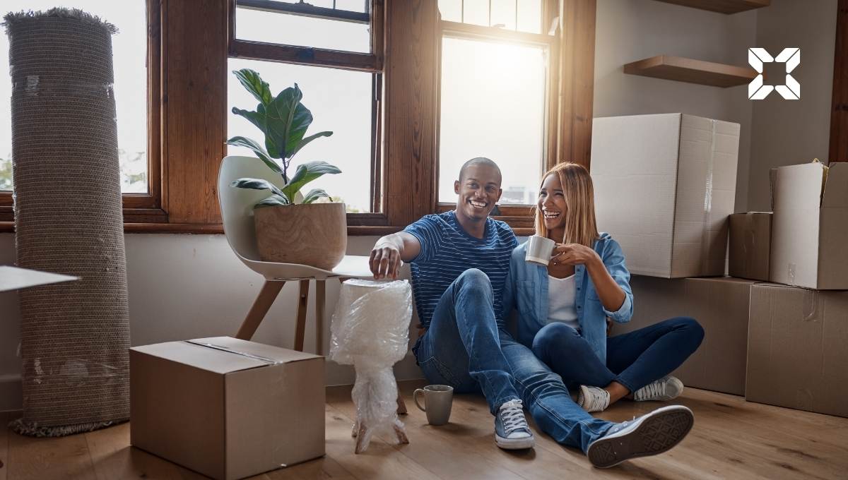 Couple sit in new home surrounded by moving boxes