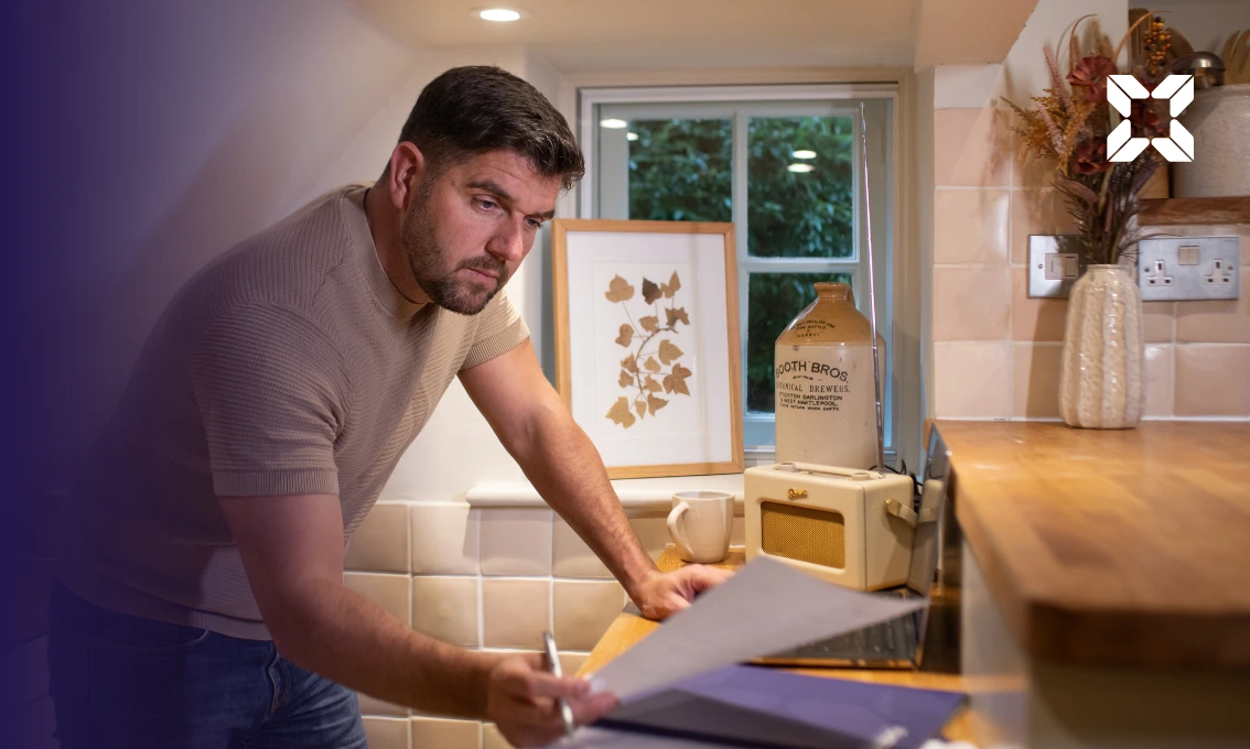 A man leaning over a desk looking at paperwork.