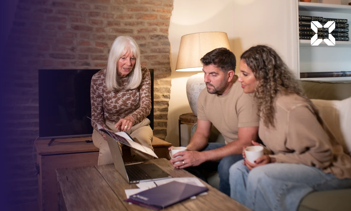 A young couple sat at a coffee table discussing finances with an older member of the family.