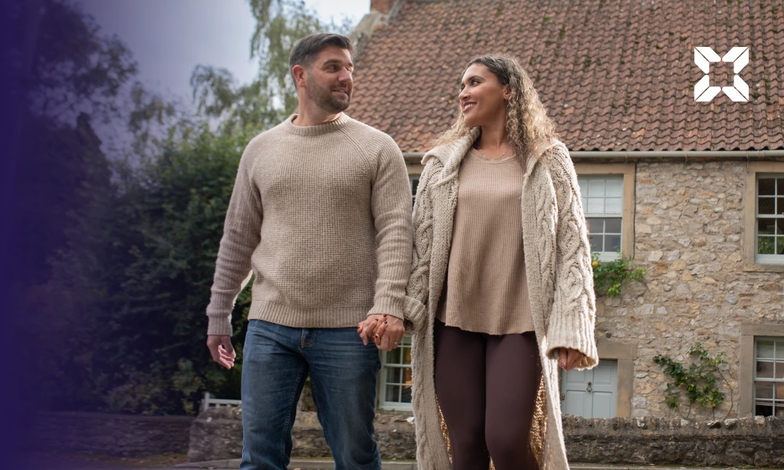 A young couple hand in hand with a house in the background